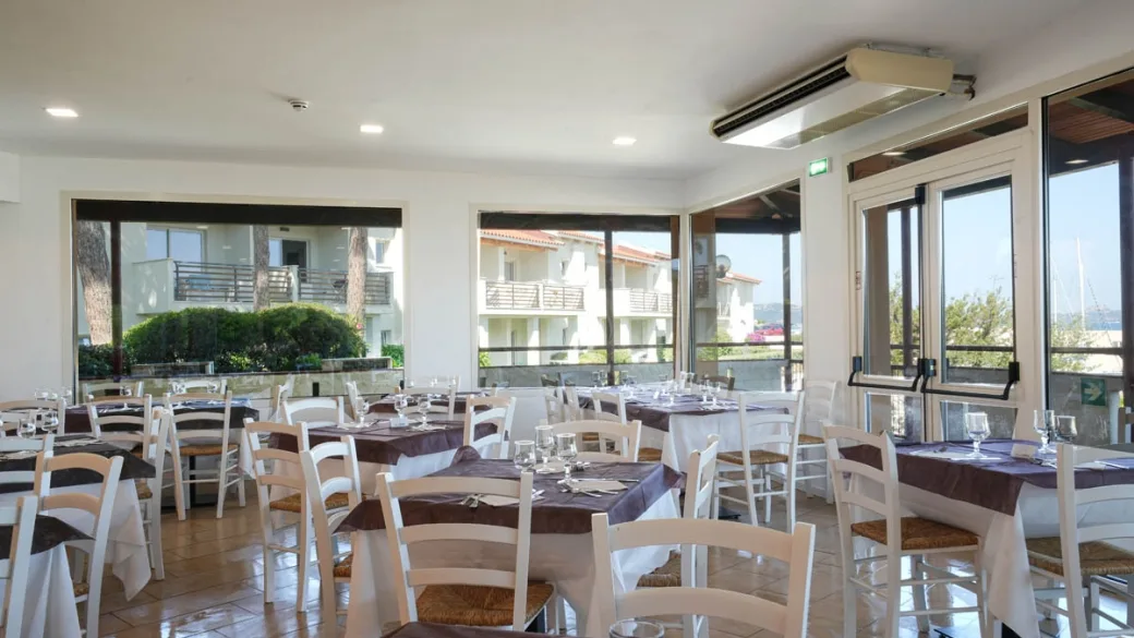 Sala ristorante con tavoli apparecchiati e ampie vetrate luminose