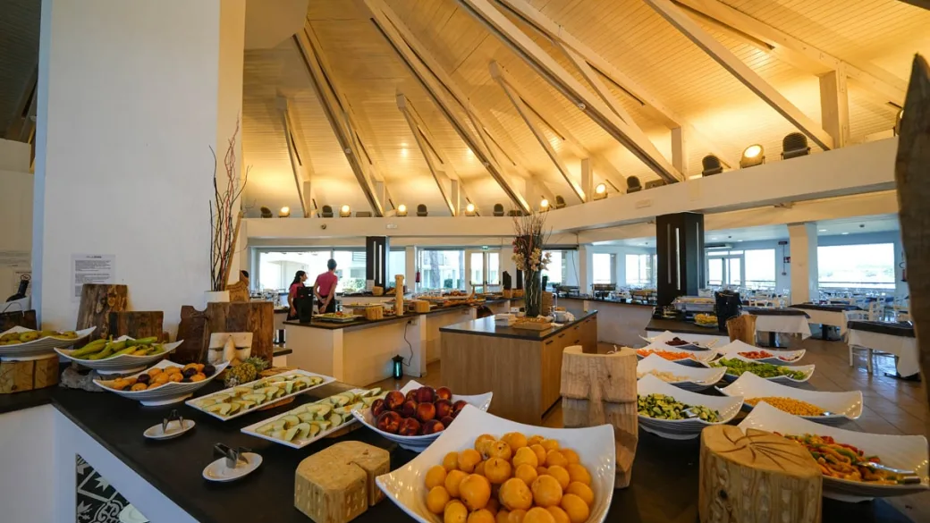 Sala buffet con frutta fresca e piatti vari sotto soffitto in legno