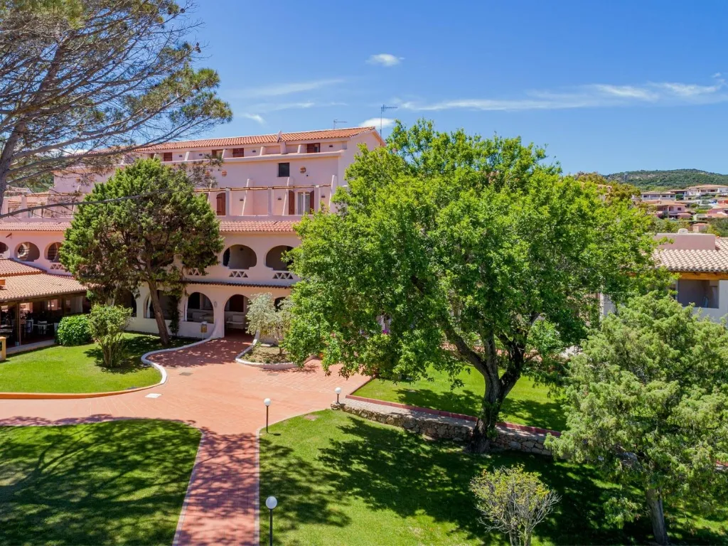 Edificio dell'hotel con portici e ampio giardino con alberi