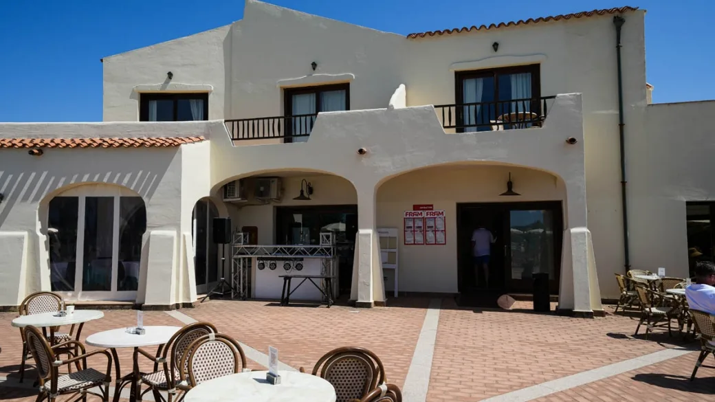 Facciata esterna dell'edificio bianco con archi e tavolini del bar all'aperto
