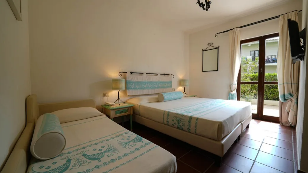 Camera con letto matrimoniale e letto singolo, decori turchesi e porta finestra sul giardino