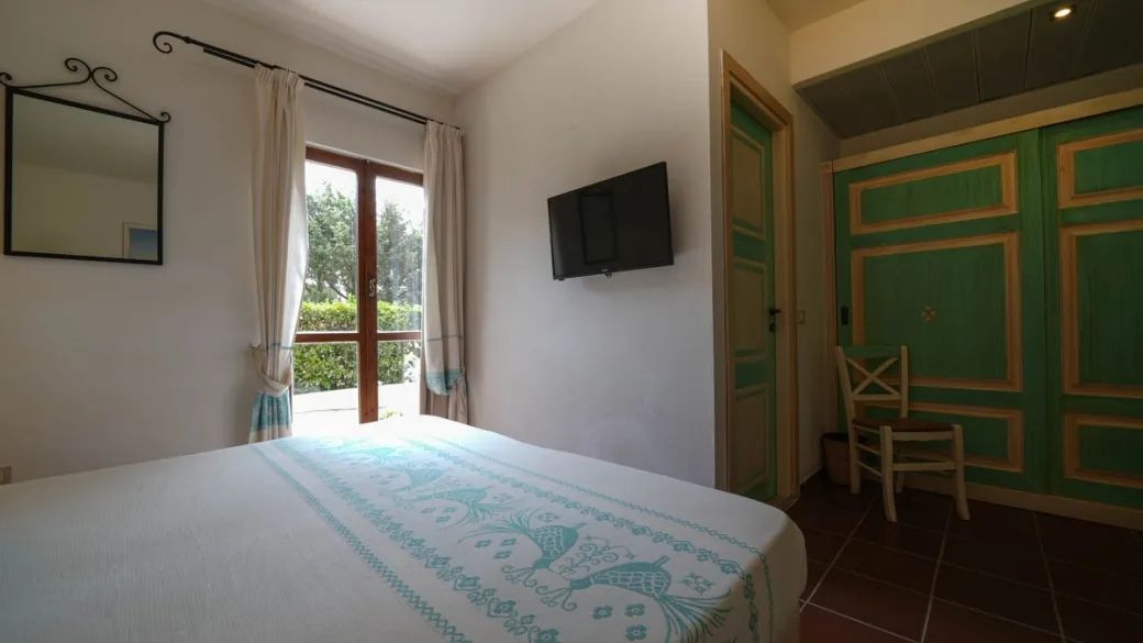 Camera con letto matrimoniale, armadio verde e finestra con vista sul verde