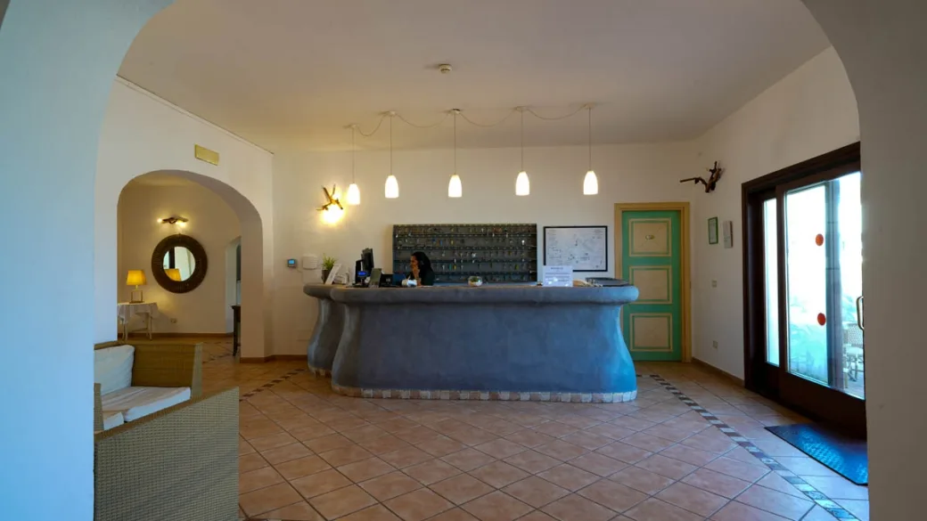 Hall e reception dell'hotel con bancone in muratura grigia e arredi in stile mediterraneo