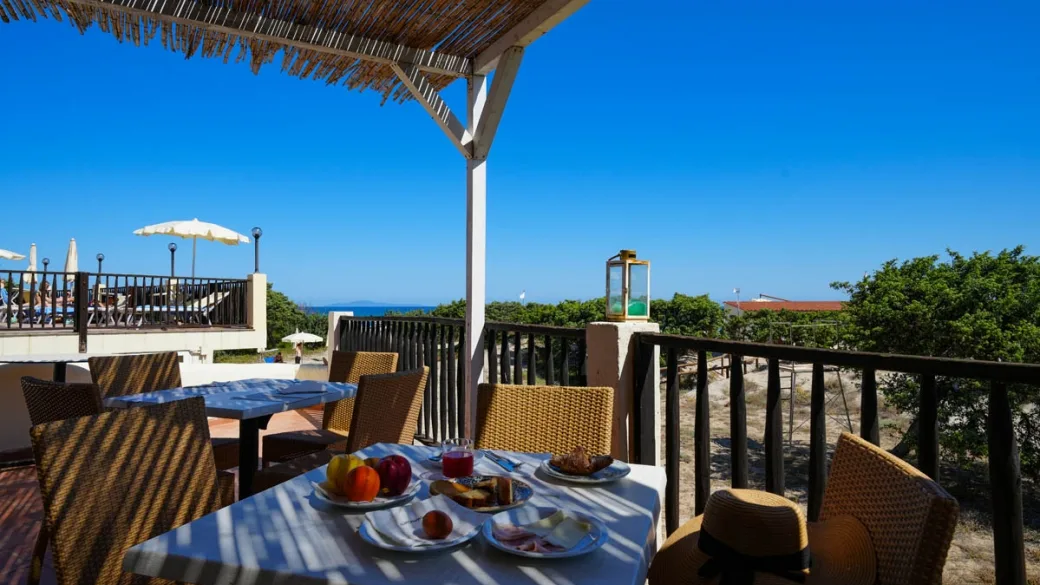 Colazione servita su terrazza con pergolato in canne e vista sul mare