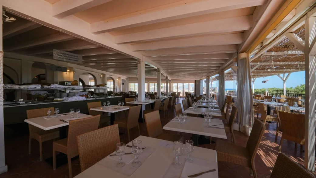 Sala ristorante interna con buffet, tavoli apparecchiati e soffitto con travi