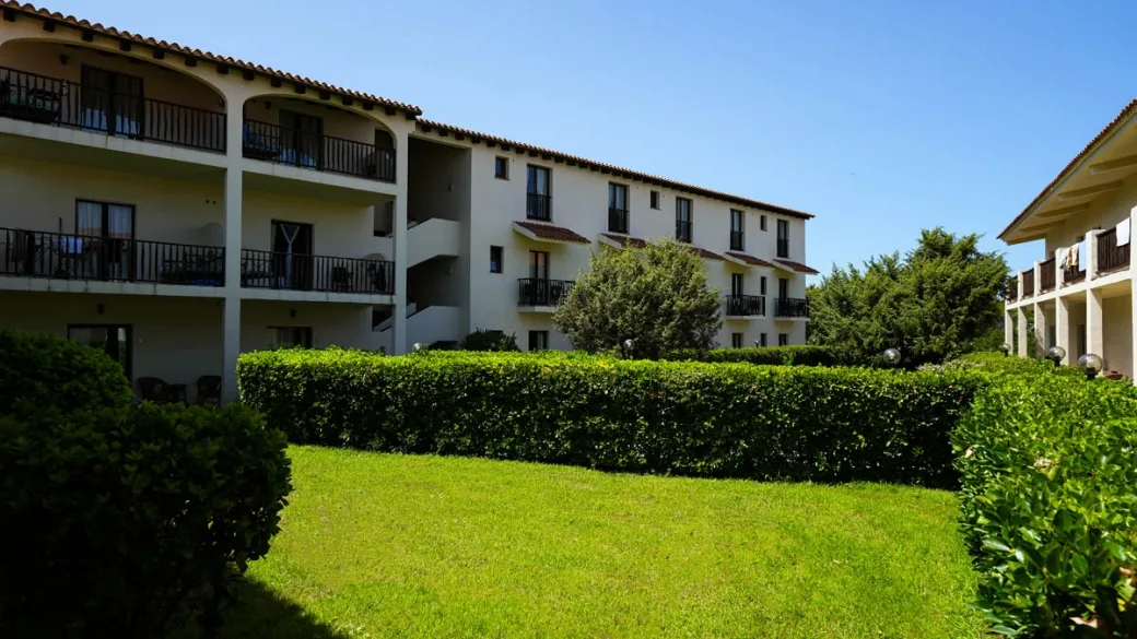 Esterno dell'edificio dell'hotel con balconi, giardino curato e siepi verdi