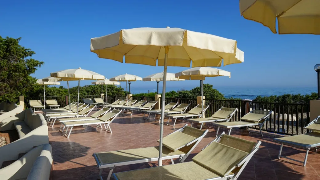 Terrazza solarium con lettini e ombrelloni gialli affacciata sul mare