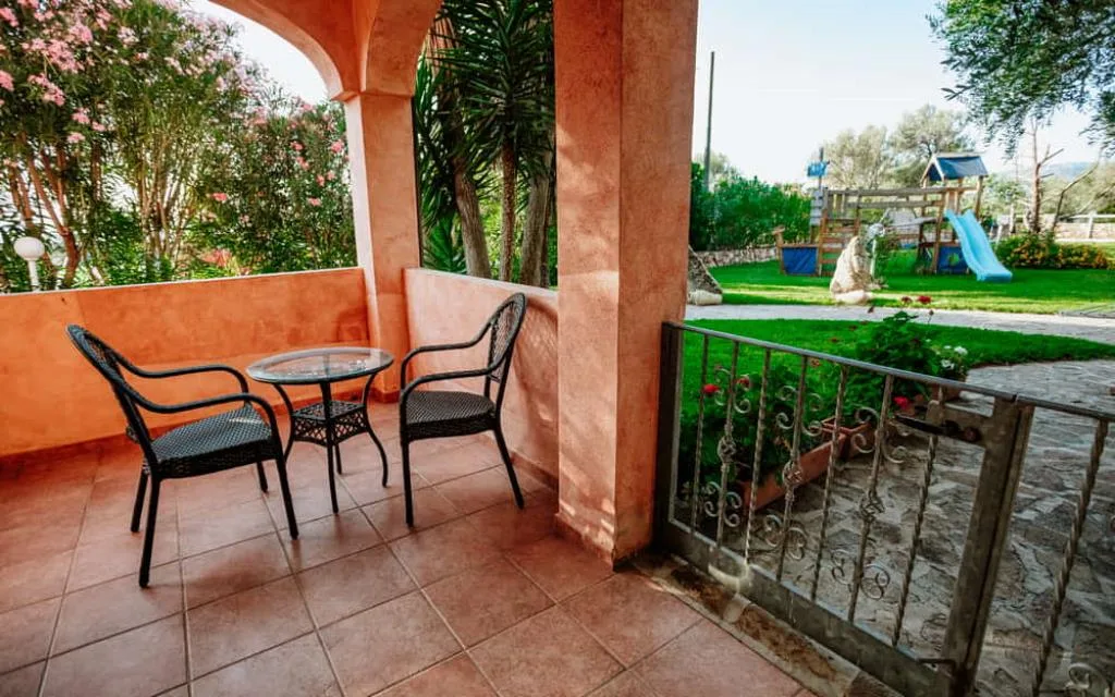 Terrazza privata con tavolino, sedie in rattan e vista sul giardino con area giochi per bambini