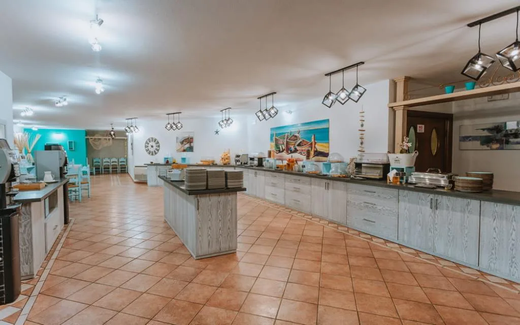 Sala colazione con ampio buffet, mobili in legno chiaro e pavimento in cotto