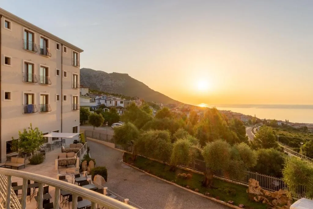 Vista dell'hotel al tramonto con terrazza, uliveti e panorama sul mare e sul paese