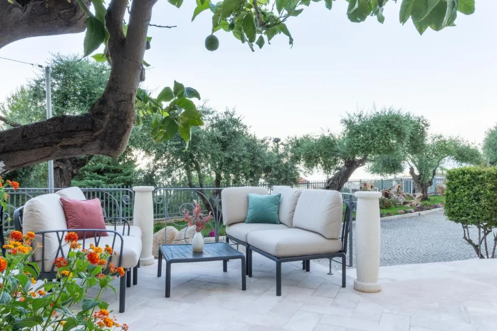 Angolo lounge esterno con divani imbottiti, cuscini colorati e fiori nel giardino