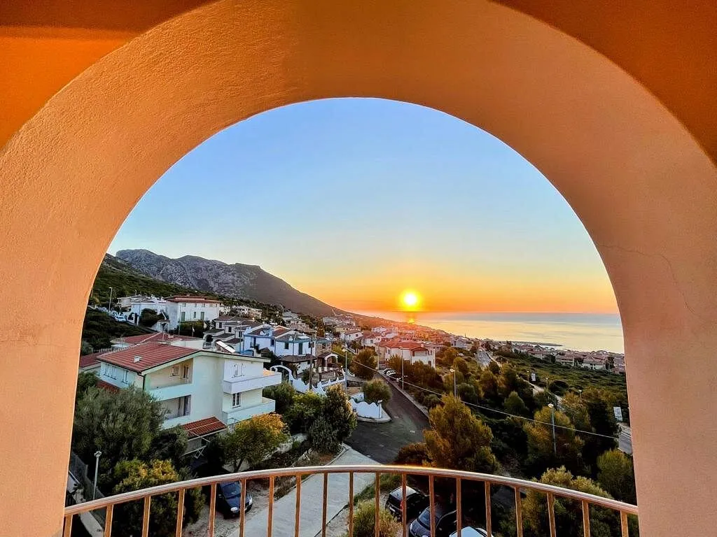 Vista del tramonto sul mare e sul paese attraverso un arco del balcone