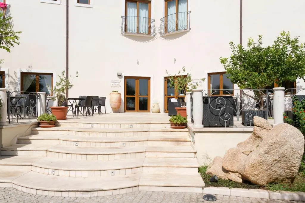 Ingresso esterno dell'hotel con scalinata in pietra, piante e roccia decorativa