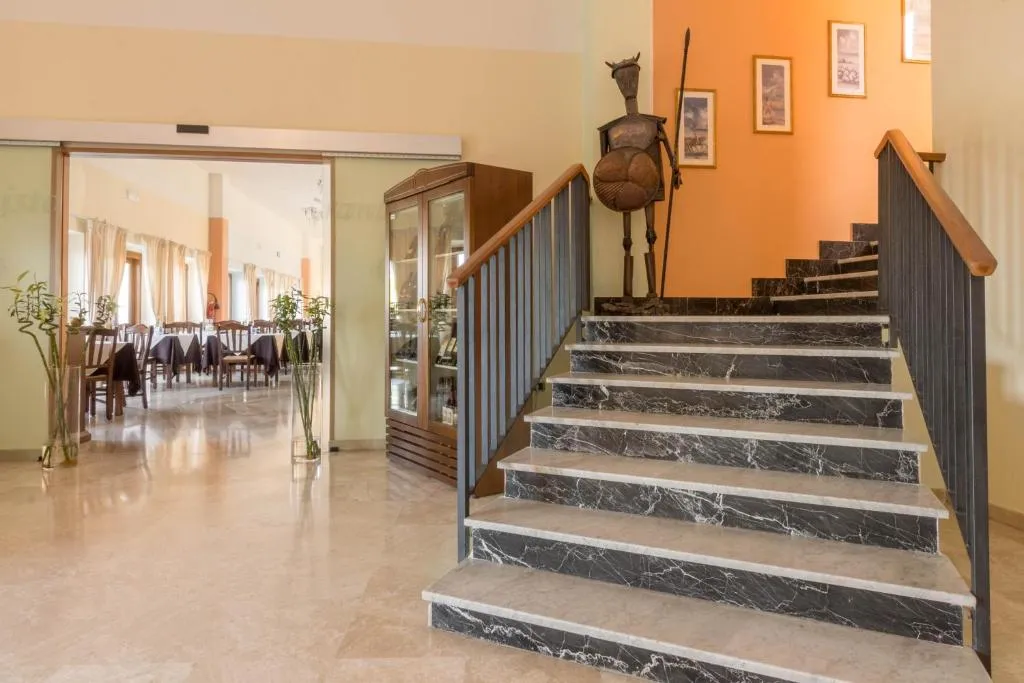 Hall interna con scala in marmo, statua decorativa e sala ristorante sullo sfondo