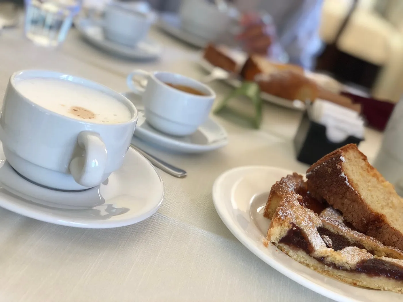Colazione con cappuccino, caffè e fetta di crostata su tavolo del ristorante