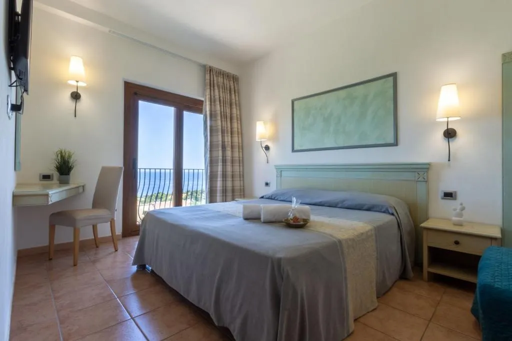 Camera matrimoniale con balcone e vista mare, scrivania e tonalità azzurre