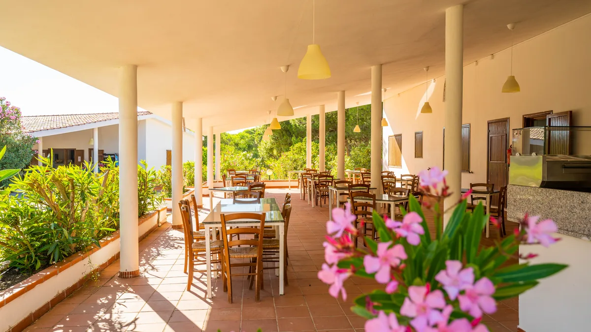Terrazza ristorante coperta con tavoli in legno e fiori rosa