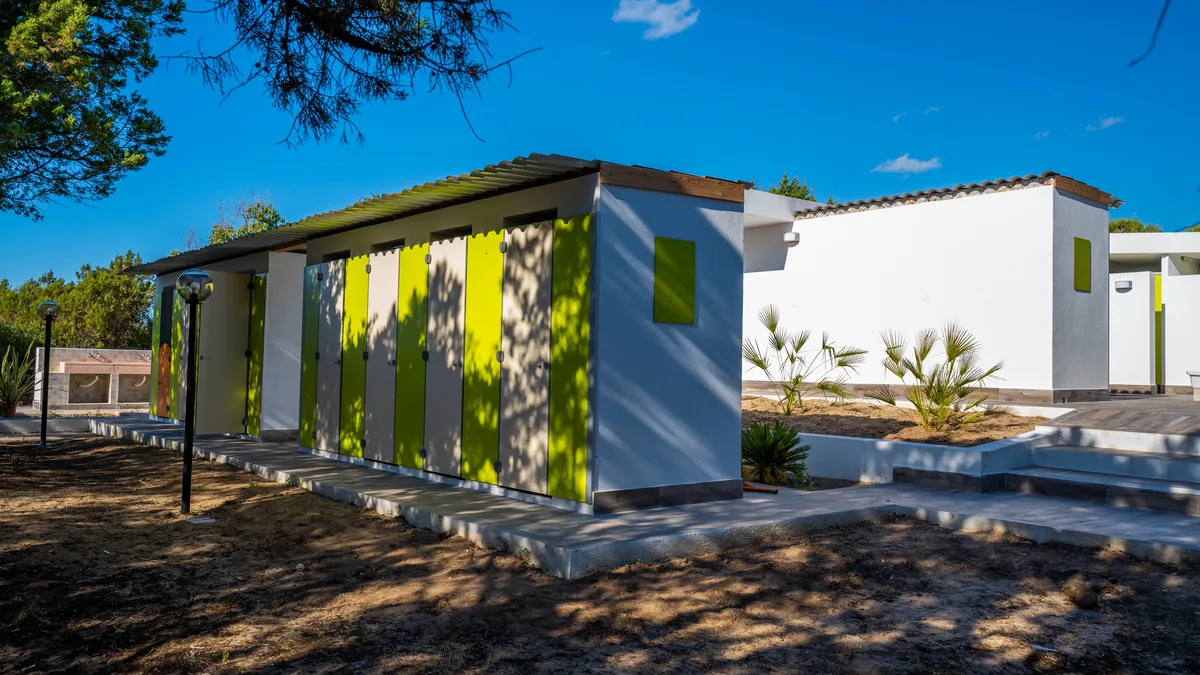 Edificio servizi igienici moderno con porte verdi all'esterno