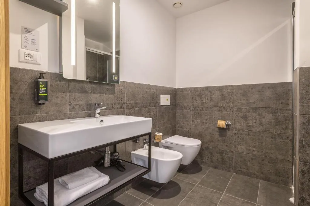 Bagno moderno con lavabo, WC, bidet e piastrelle grigie