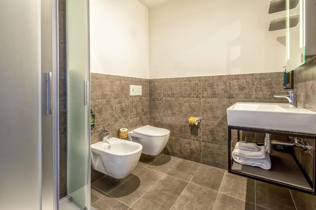 Bagno con doccia, WC, bidet, lavabo e piastrelle grigie