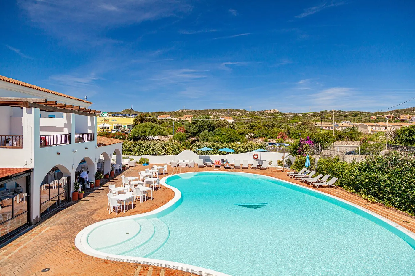 Piscina con terrazza solarium, tavoli del ristorante e vista sulle colline circostanti