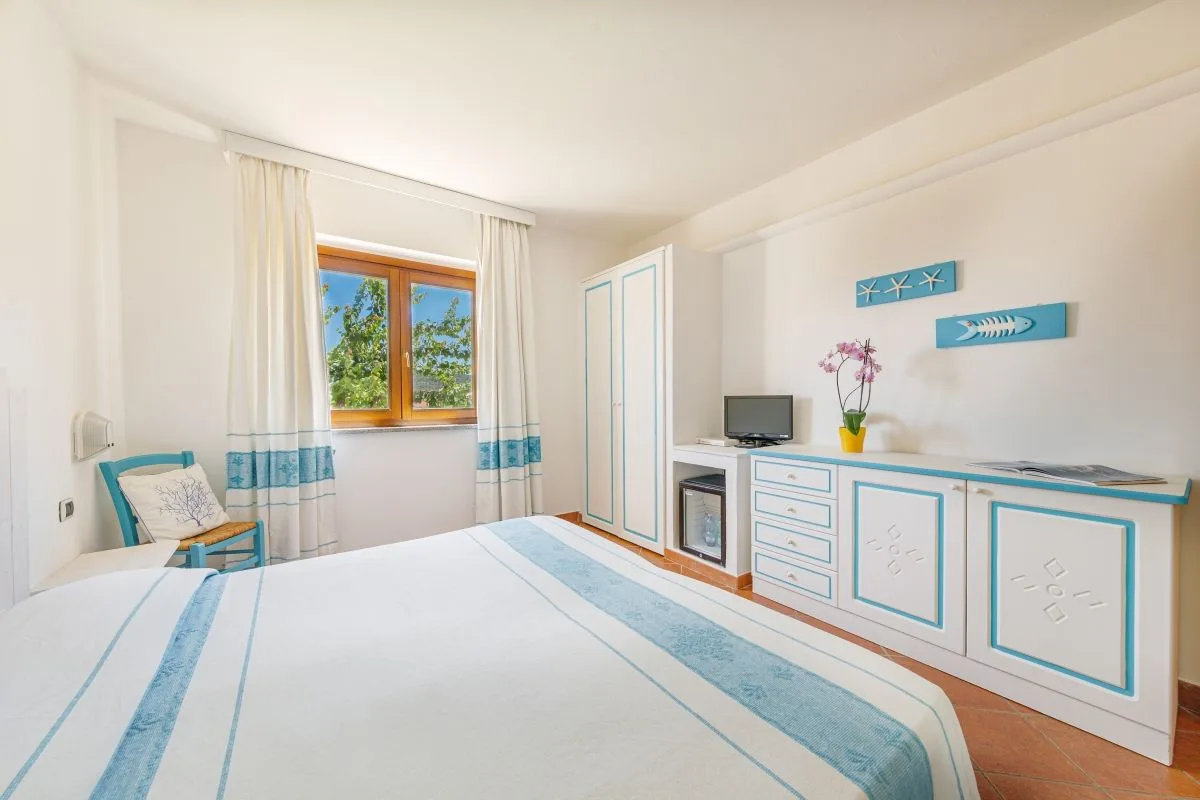 Camera con finestra, armadio bianco e azzurro e decorazioni a tema marino sulla parete