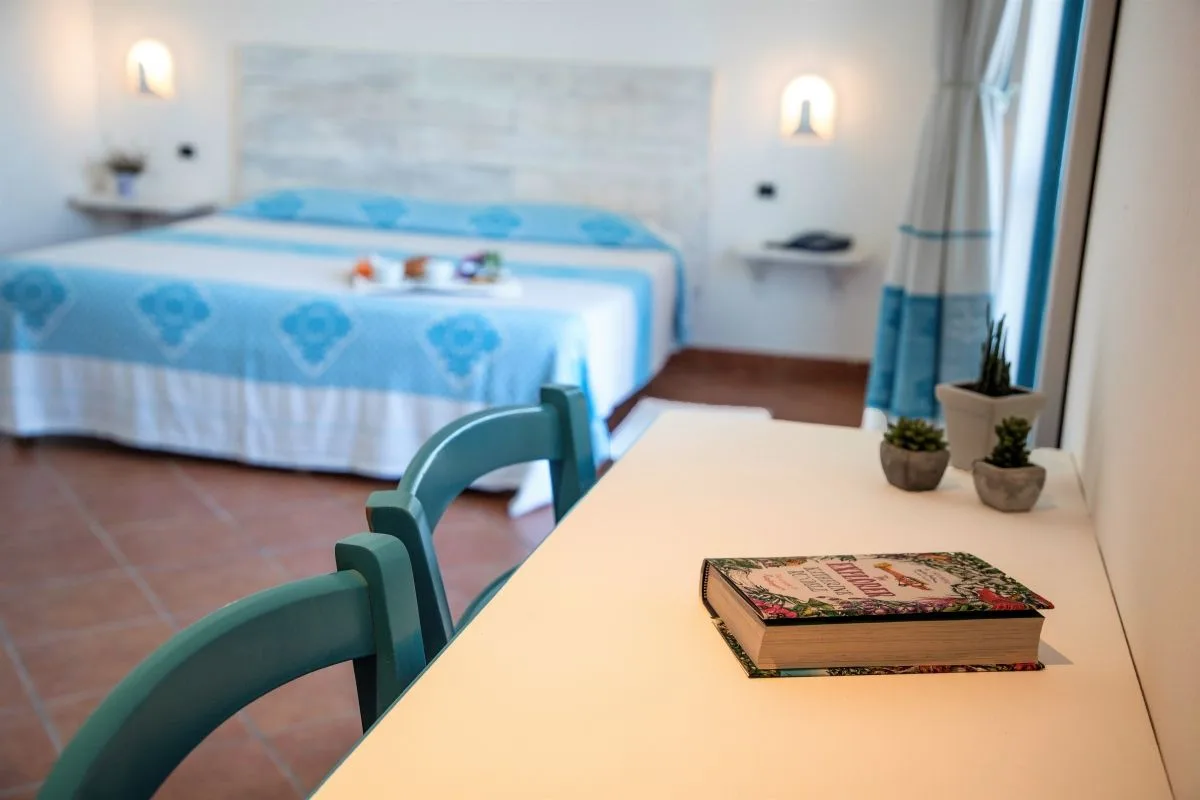 Camera con letto matrimoniale, vassoio colazione e angolo scrivania con sedie verdi