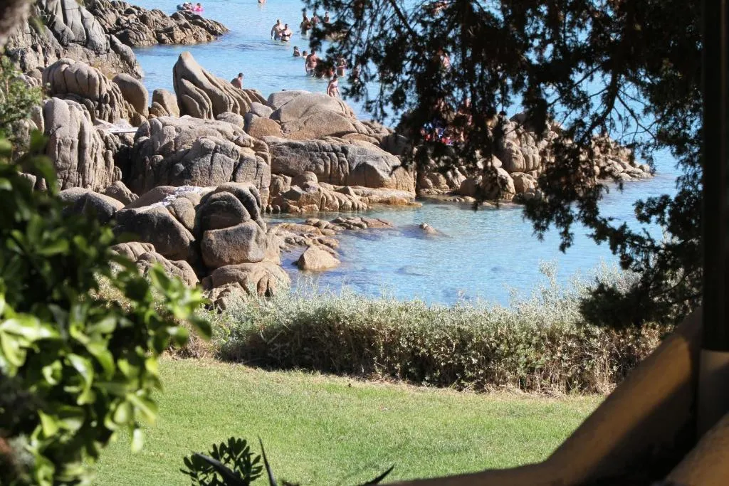Scorcio del mare tra le rocce di granito con bagnanti e vegetazione