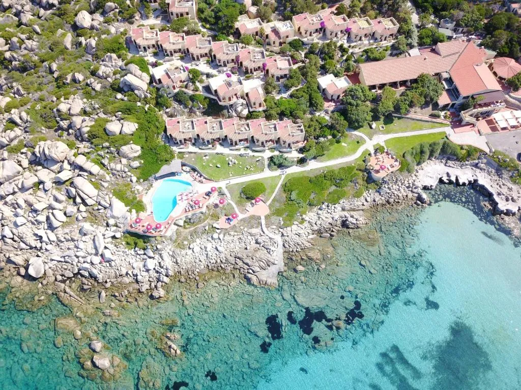 Veduta aerea del resort con piscina, ville e mare cristallino sulla costa
