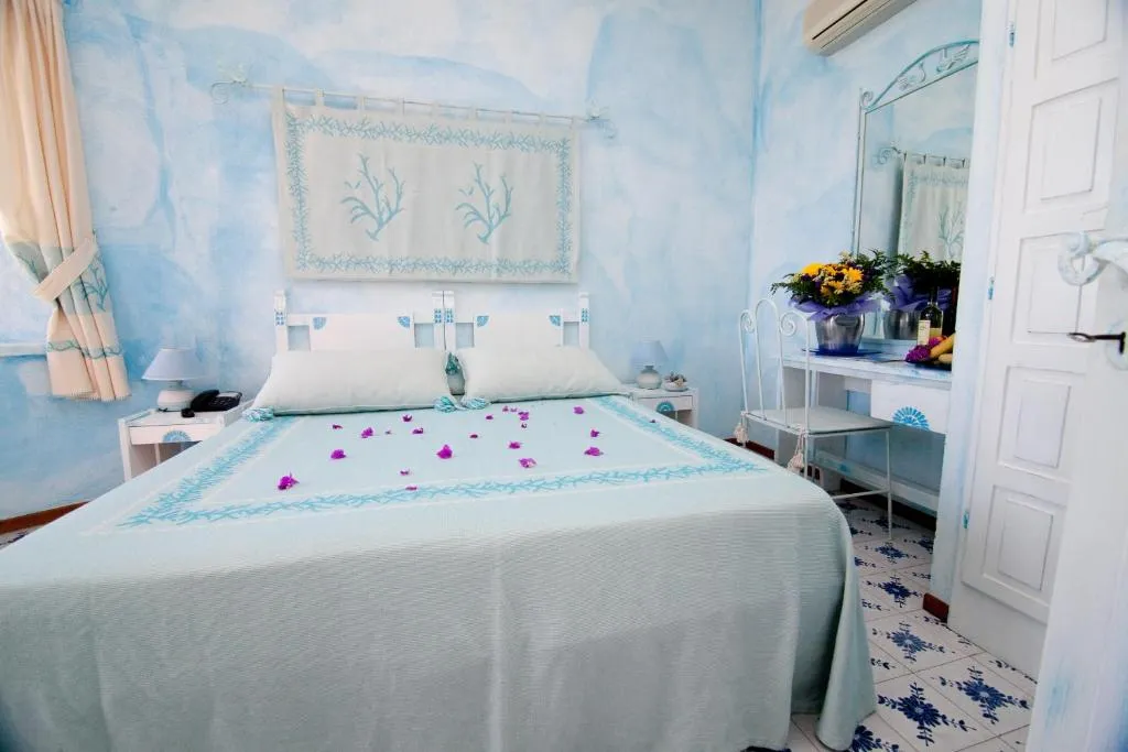 Camera matrimoniale in stile mediterraneo con pareti azzurre e decori floreali