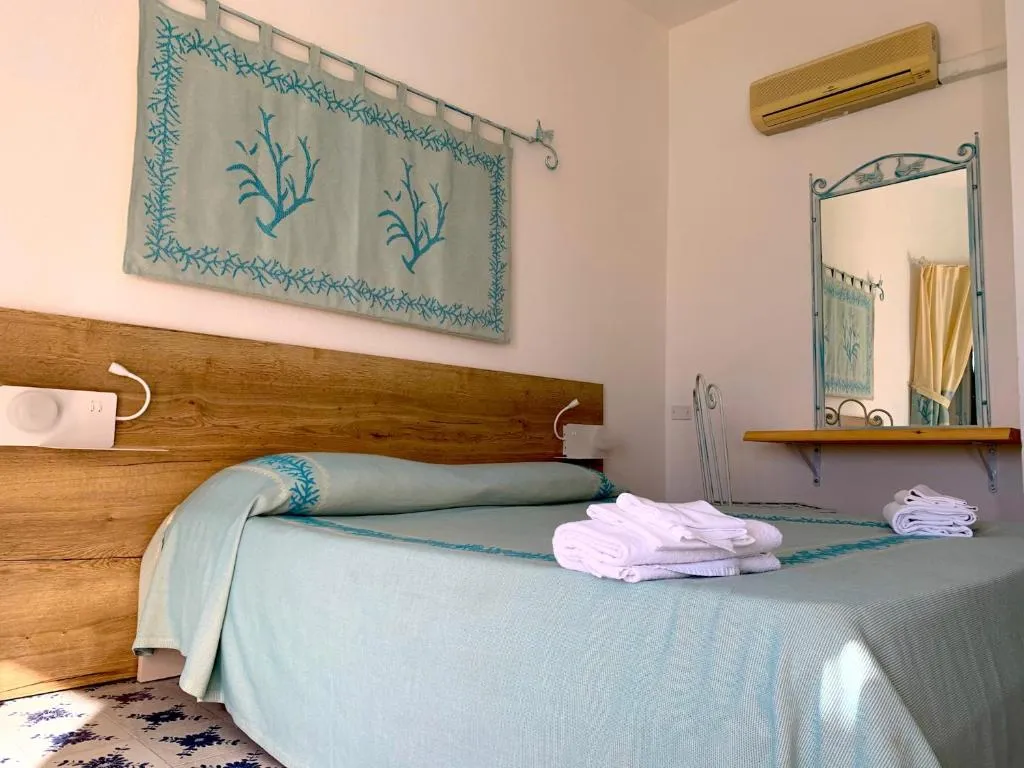 Letto matrimoniale con asciugamani, decoro a coralli e specchio in ferro battuto
