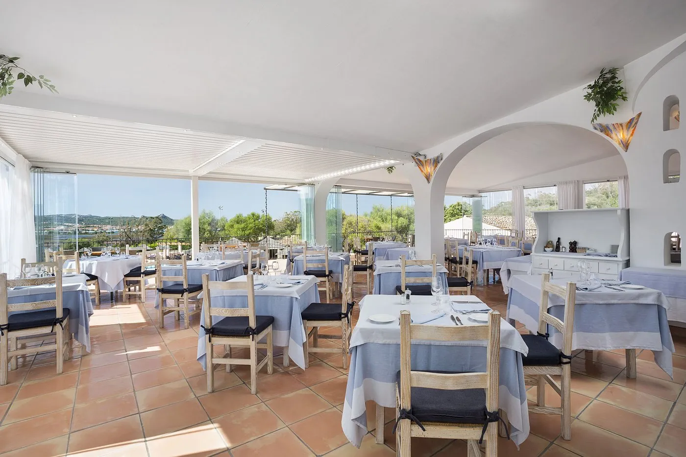 Sala ristorante luminosa con tavoli apparecchiati in azzurro e ampie vetrate panoramiche