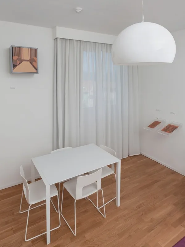 Zona pranzo con tavolo e sedie bianche, grande lampada a sospensione e parquet