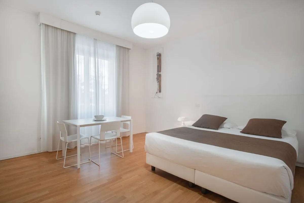 Camera spaziosa con letto matrimoniale e tavolo da pranzo vicino alla finestra