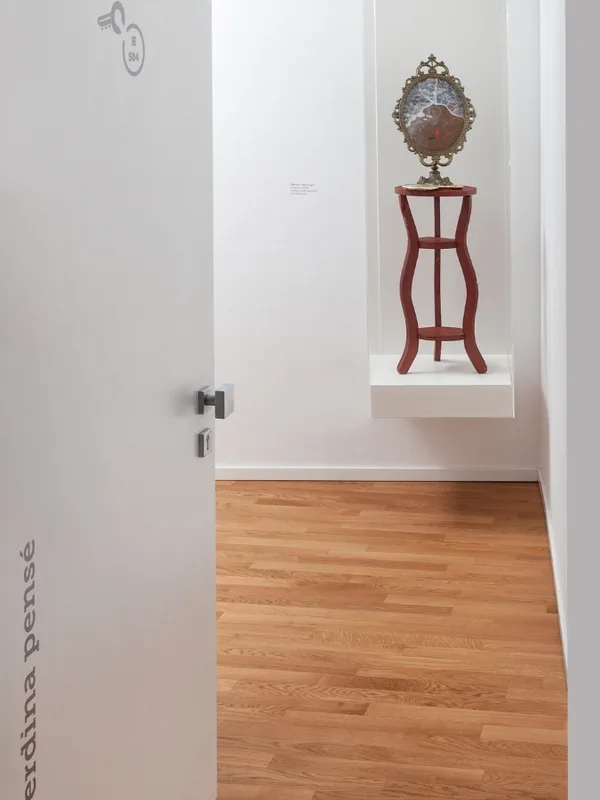 Corridoio bianco con opera d'arte e tavolino rosso decorativo