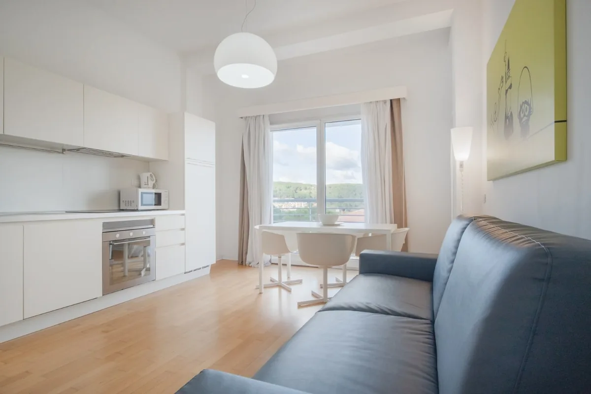 Soggiorno con divano blu, cucina bianca e tavolo da pranzo con vista panoramica
