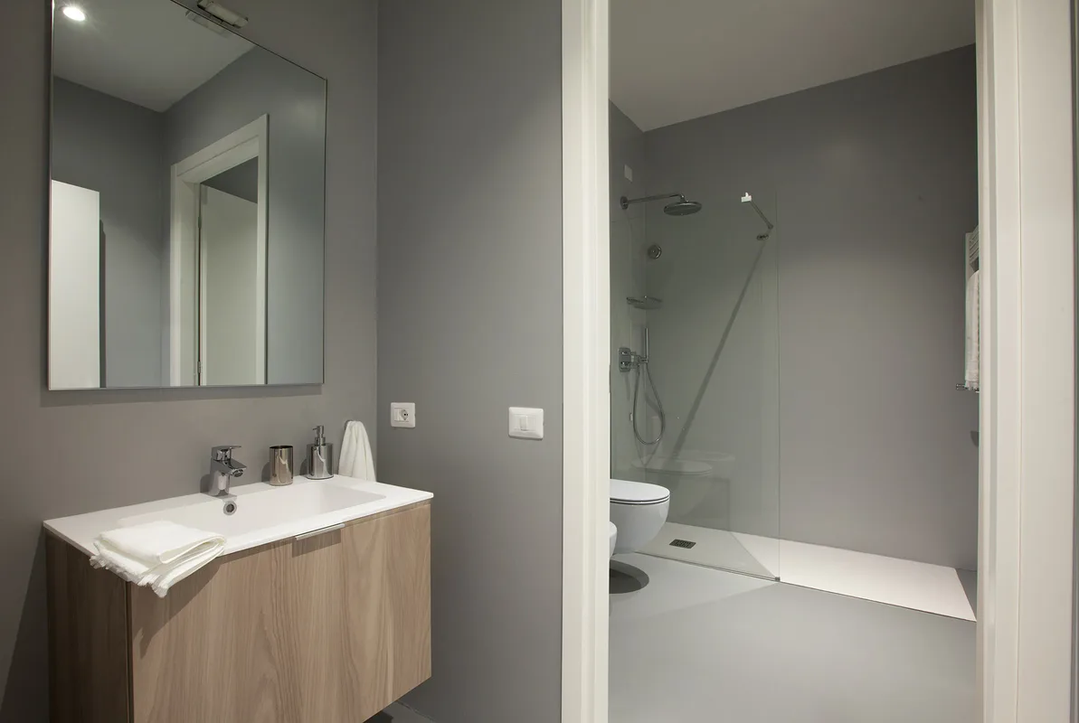 Bagno moderno con lavabo in legno, specchio e doccia a pavimento grigia