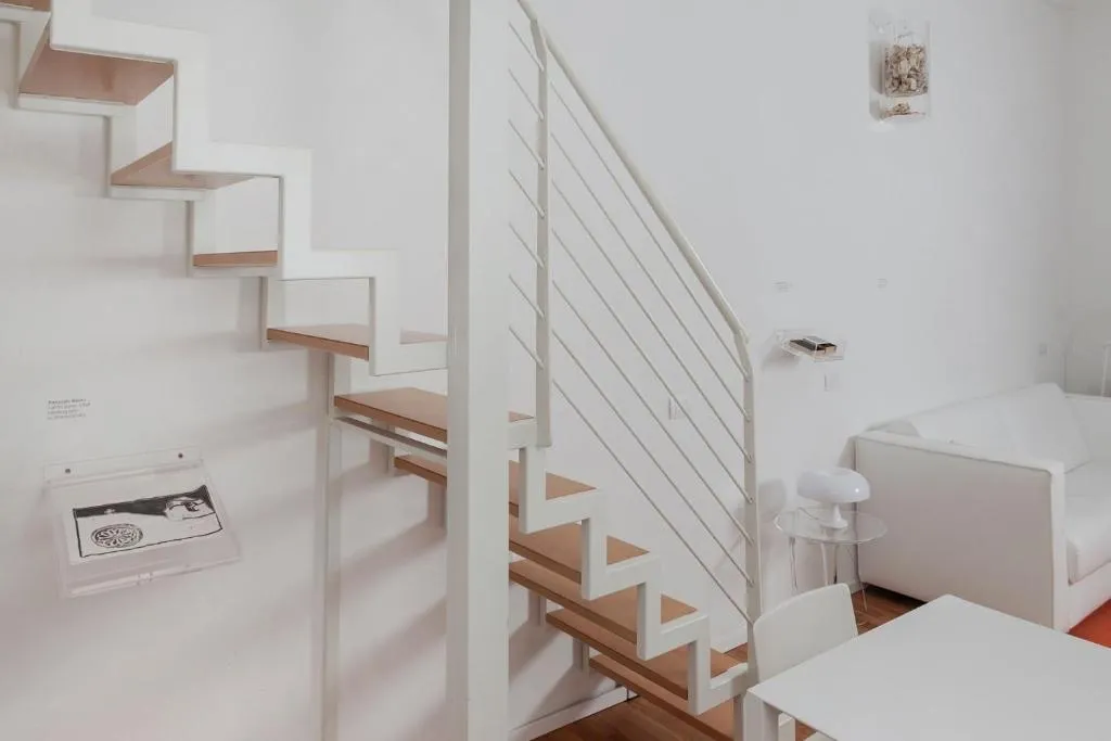 Scala interna bianca in legno con divano e dettagli minimalisti nell'appartamento