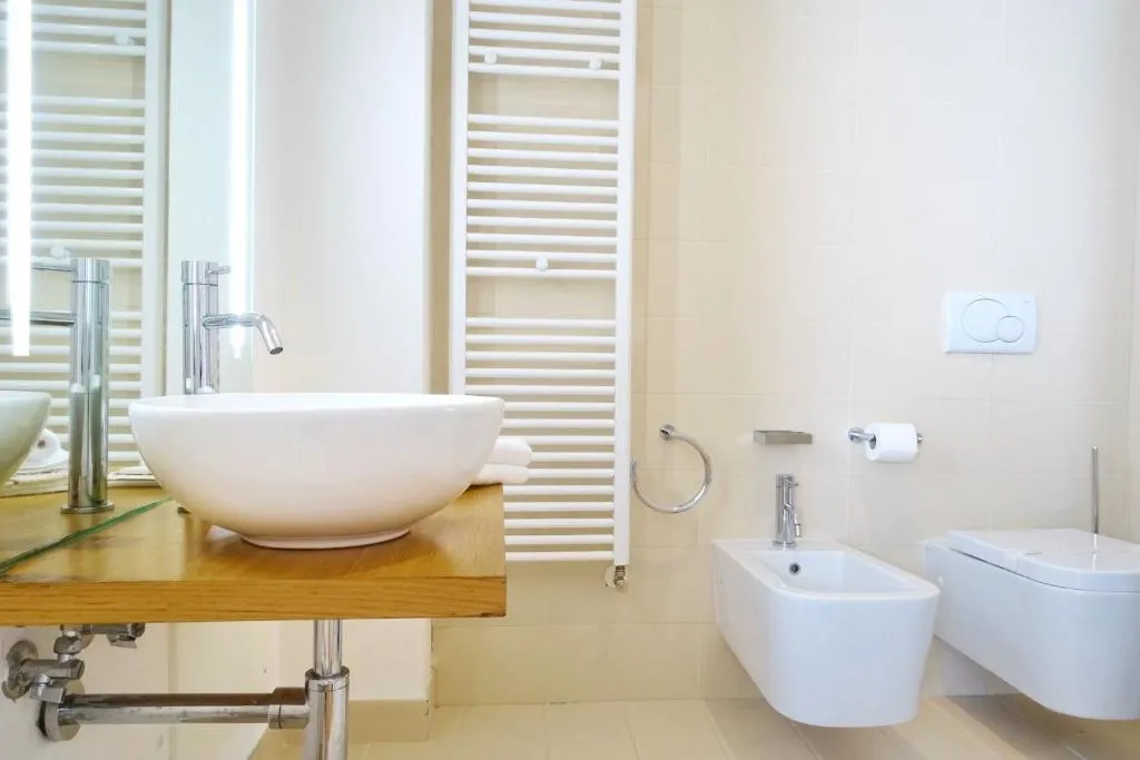 Bagno elegante con lavabo a catino su mensola in legno, bidet e WC sospesi