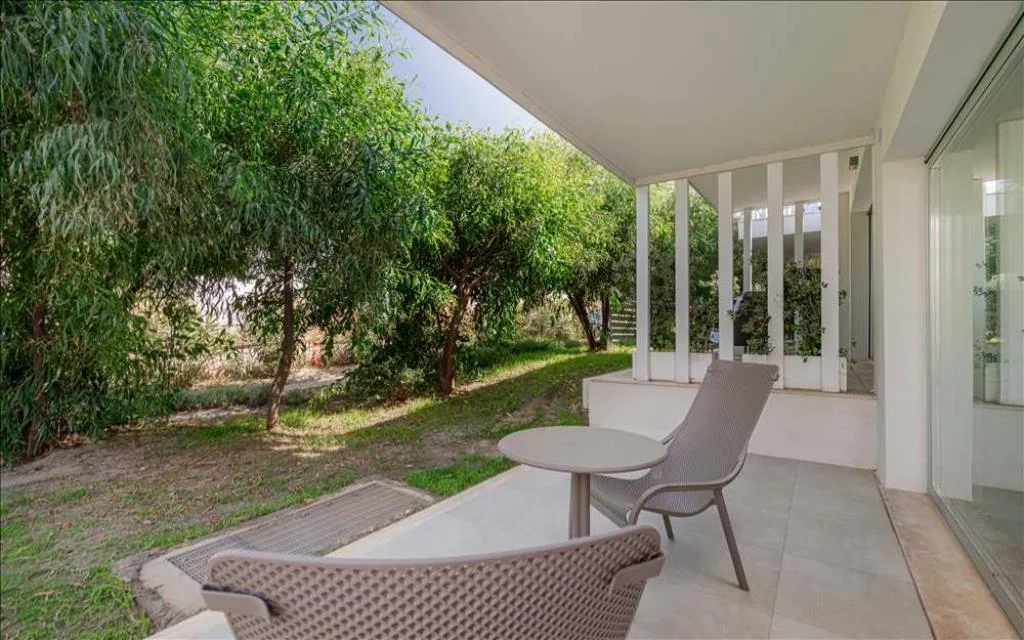 Veranda con poltroncine e tavolino affacciata sul giardino alberato