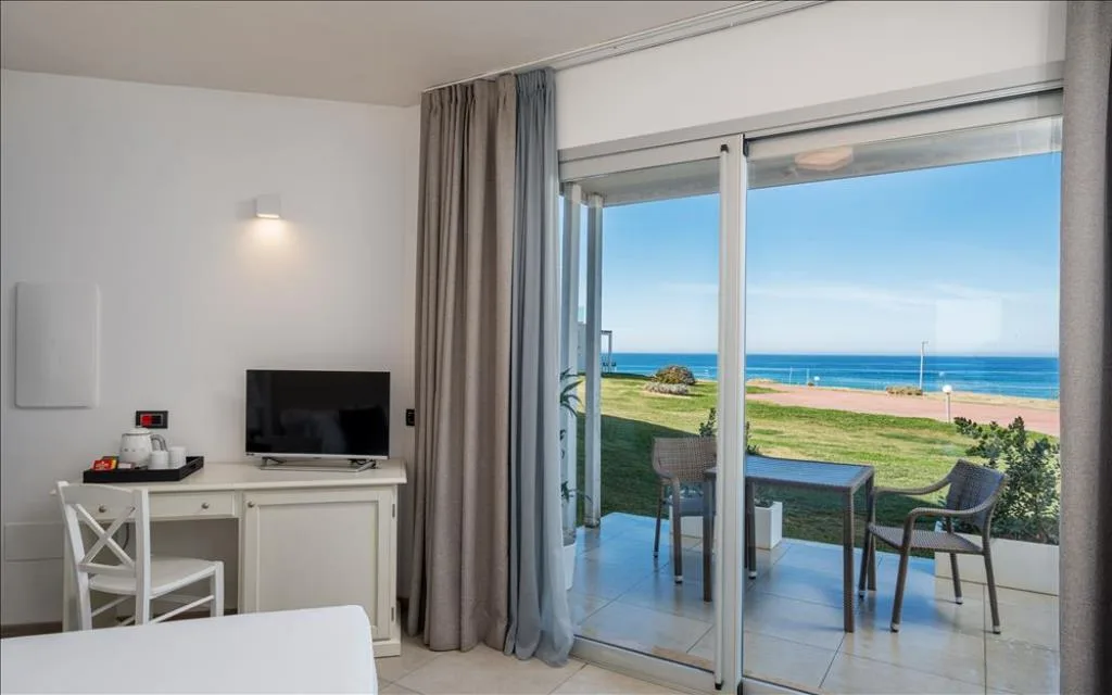 Camera con scrivania, TV e terrazza con tavolino affacciata sul mare
