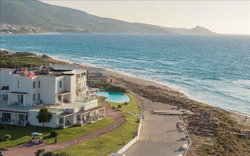 Veduta aerea del resort con piscina lungo la costa al tramonto
