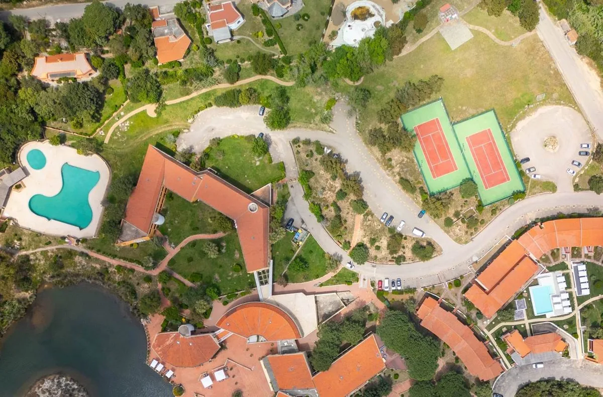 Veduta aerea dall'alto del resort con piscina, campi da tennis e giardini
