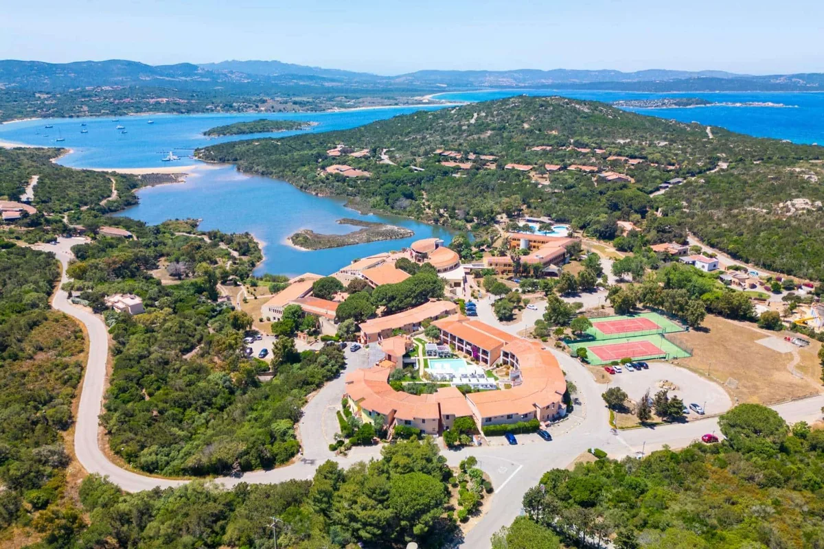 Panoramica aerea del resort tra laguna, mare e colline verdi della Sardegna