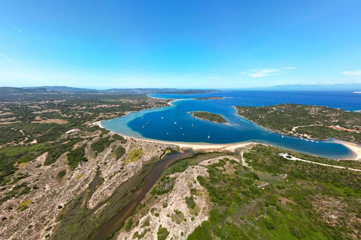 Veduta aerea di laguna azzurra con barche e spiaggia sabbiosa lungo la costa