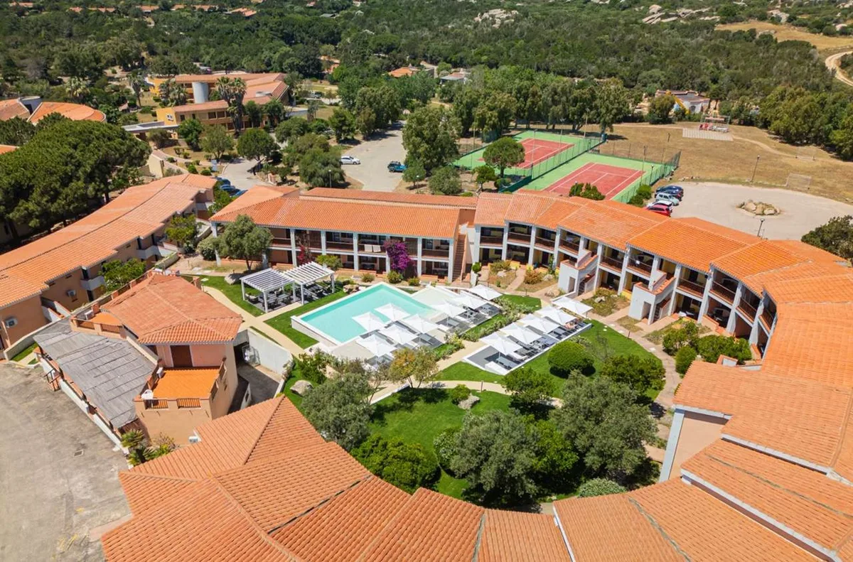 Veduta aerea della piscina del resort con lettini, ombrelloni e campi da tennis