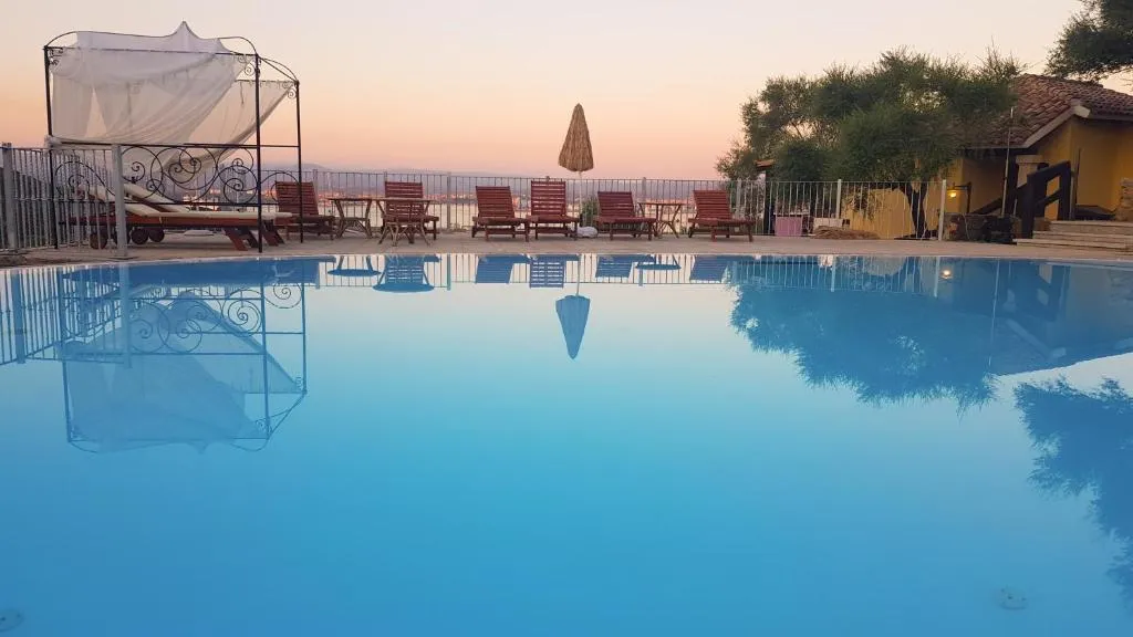 Piscina al tramonto con riflessi, lettini e gazebo con vista sul mare