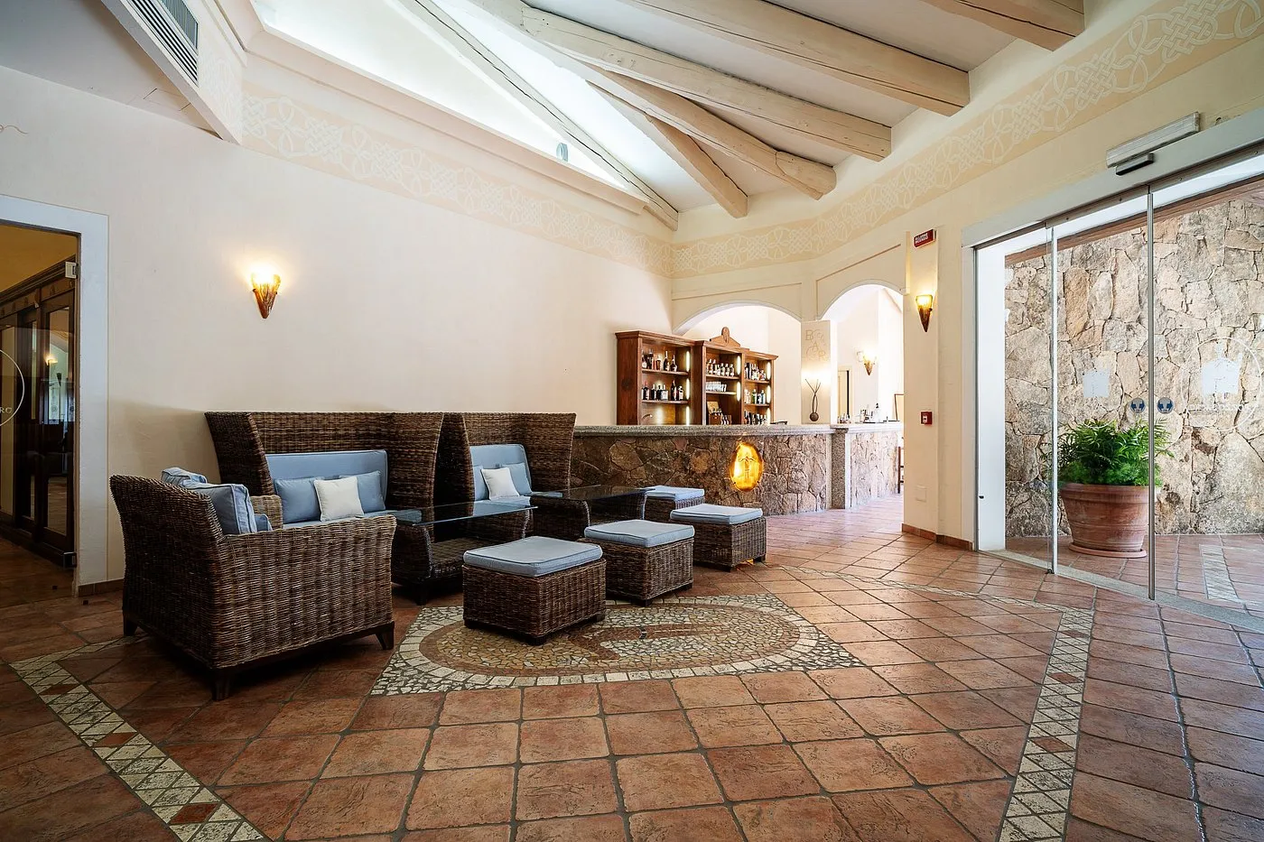 Hall dell'hotel con divani in vimini, bar in pietra e pavimento in cotto
