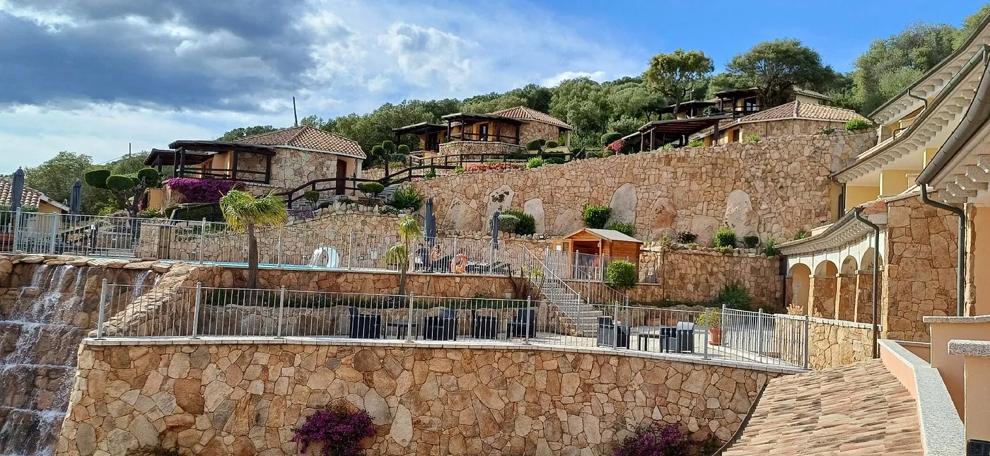 Veduta degli edifici dell'hotel su terrazzamenti in pietra con cascata e vegetazione