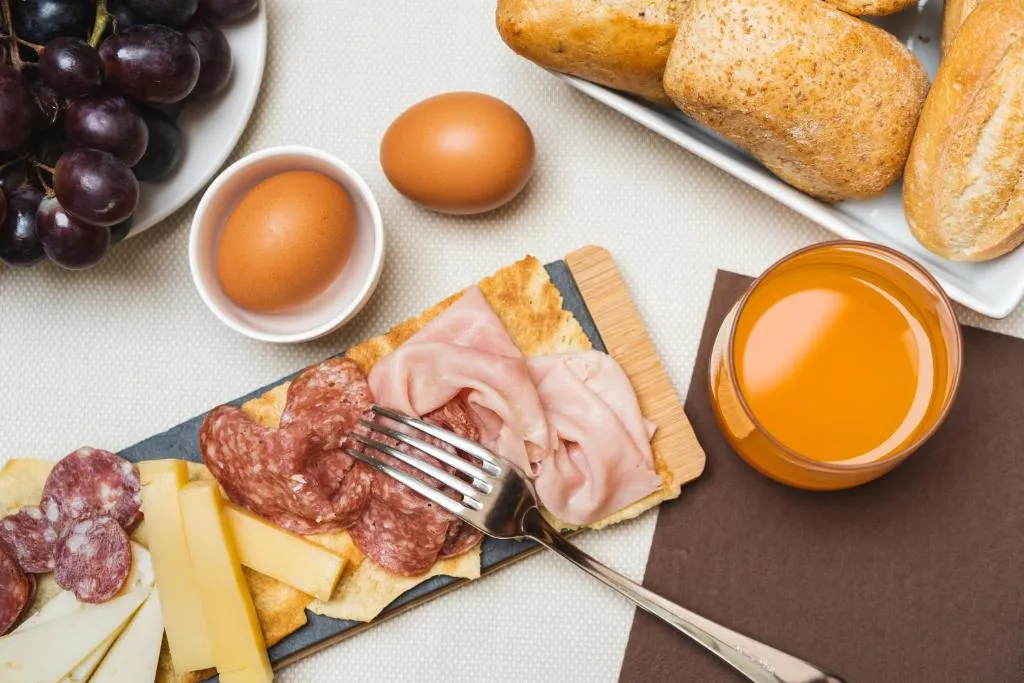 Colazione con affettati, formaggi, uova, pane e succo d'arancia